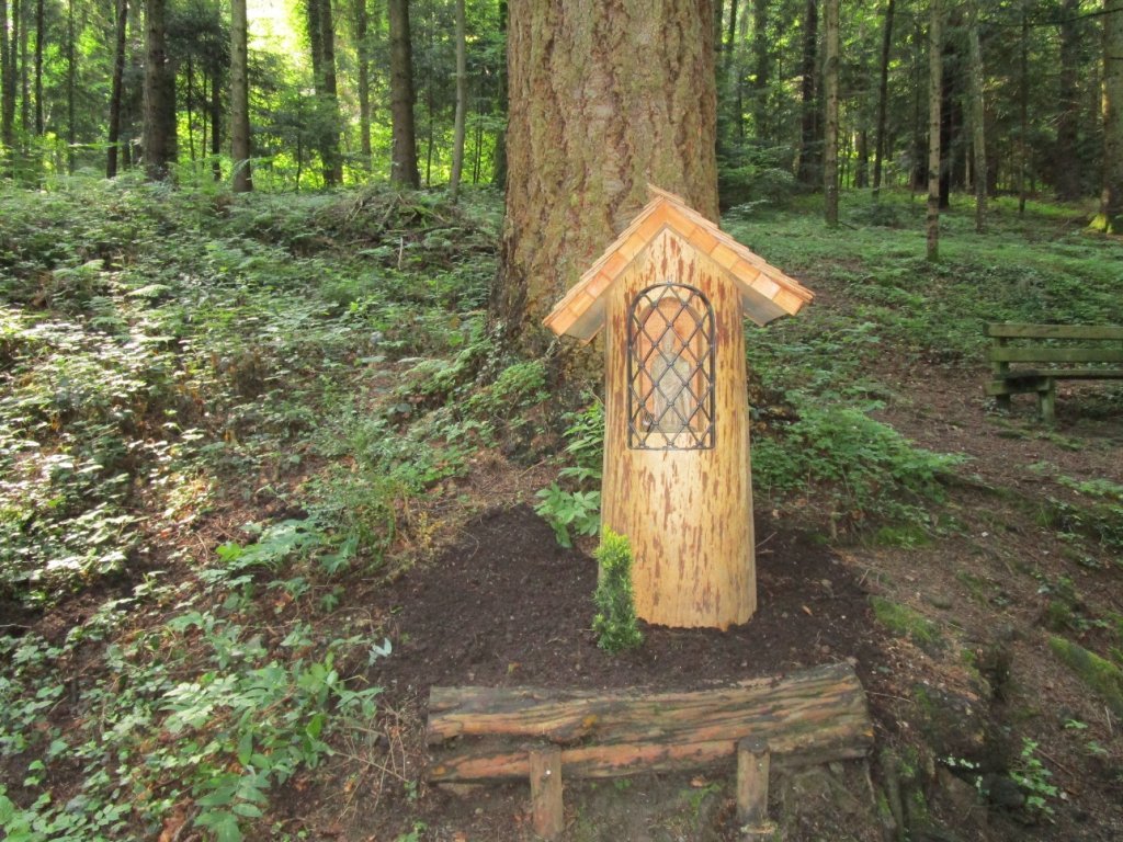 Ein hölzernes Materl vor einer mächtigen Douglasie am Waldlehrpfad im Stadtwald